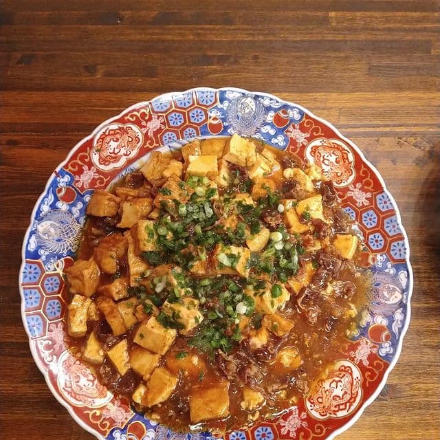 色絵の大皿に盛りつけた、青ねぎをちらした熱々の麻婆豆腐