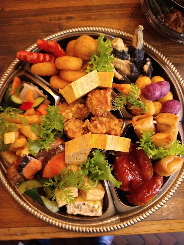 仕切りのある銀の器に、揚げ物や焼き魚、酢の物を彩りよく盛り分けた和風オードブル