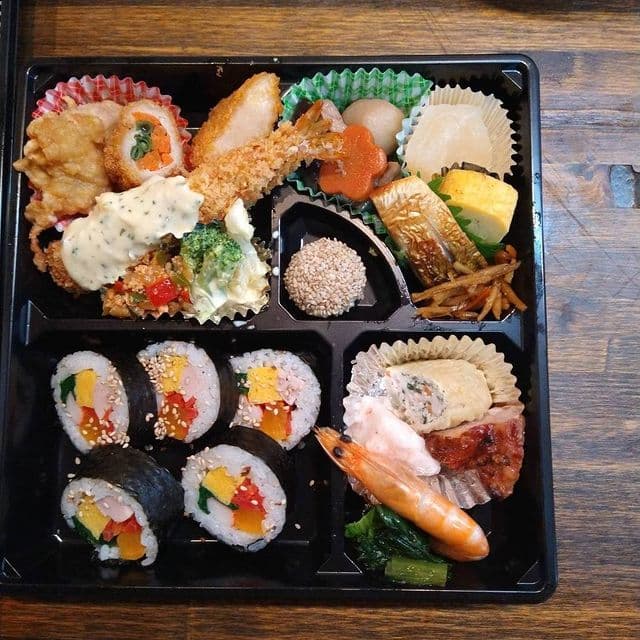 巻き寿司、エビフライ、焼き魚、煮物を詰めた幕の内弁当