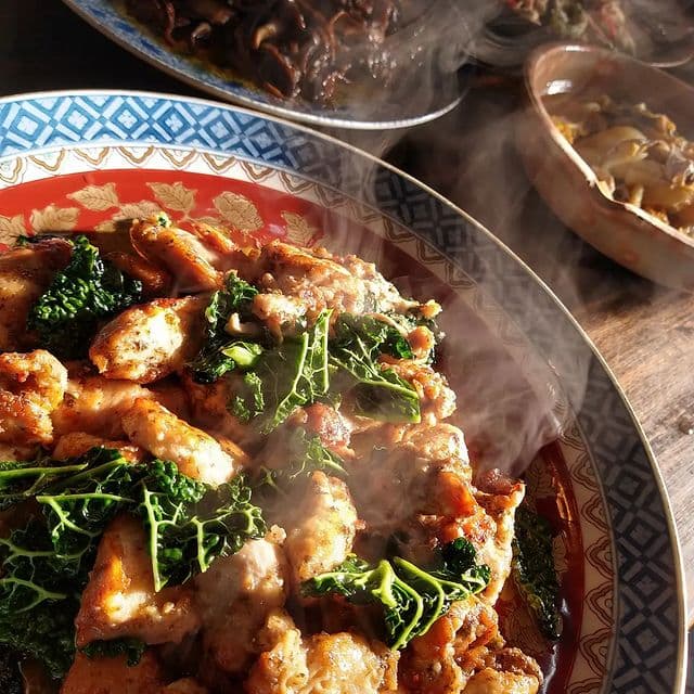 湯気の立つ、炒めたての鶏肉と青菜の惣菜。食工房ふたみの厨房にて